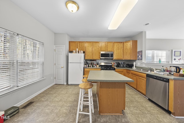 2910 Barrymore St Unit 100, Raleigh, NC 27603 - kitchen featuring appliances with stainless steel finishes, a kitchen bar, a center island, a sink, and light countertops