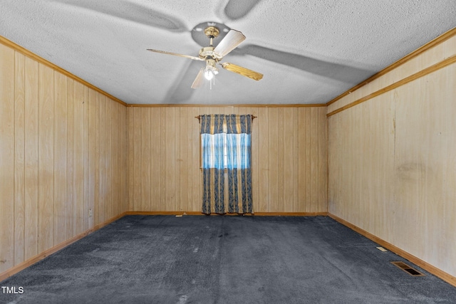 4038 Redwood Rd, Durham, NC 27704 - empty room with ceiling fan, dark carpet, a textured ceiling, wood walls, and baseboards
