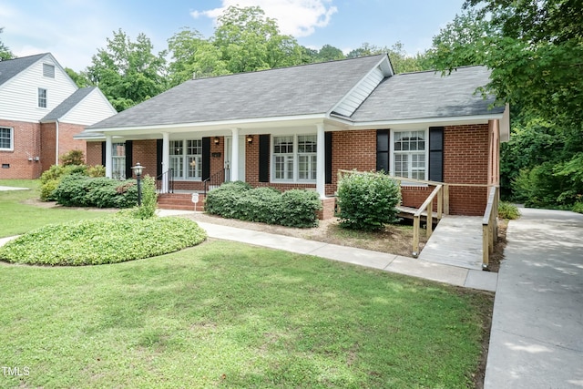 303 Spring St, Louisburg, NC 27549 - view of front of house with brick siding, a front yard, covered porch, and roof with shingles
