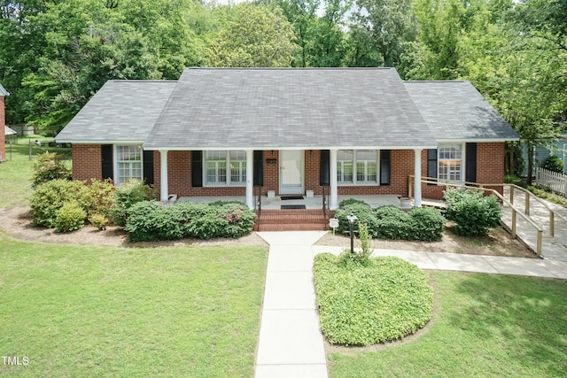 303 Spring St, Louisburg, NC 27549 - cape cod house with brick siding, a front yard, a porch, and a shingled roof