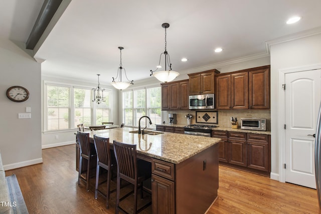 2661 Silver Bend Dr, Apex, NC 27539 - kitchen featuring stainless steel appliances, a sink, light wood finished floors, light stone countertops, and crown molding