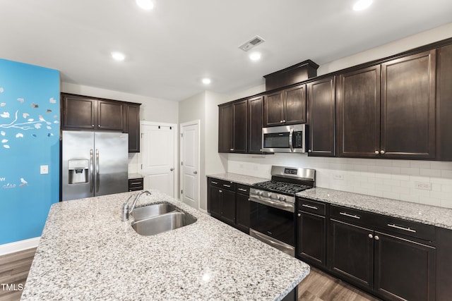 409 Rhamkatte Rd, Holly Springs, NC 27540 - kitchen featuring appliances with stainless steel finishes, a sink, wood finished floors, tasteful backsplash, and dark brown cabinets