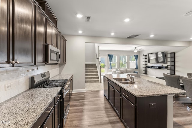 409 Rhamkatte Rd, Holly Springs, NC 27540 - kitchen with appliances with stainless steel finishes, a sink, open floor plan, wood finished floors, and recessed lighting