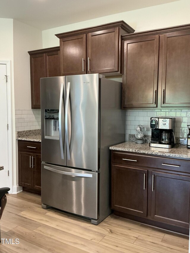 1116 Sidney Creek Dr Unit 1116, Zebulon, NC 27597 - kitchen with stainless steel fridge with ice dispenser, decorative backsplash, light wood-style floors, dark brown cabinetry, and light stone counters