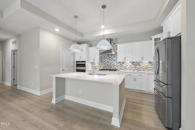 537 Bramble Ln, Clayton, NC 27527 - kitchen featuring appliances with stainless steel finishes, a tray ceiling, wall chimney range hood, tasteful backsplash, and recessed lighting