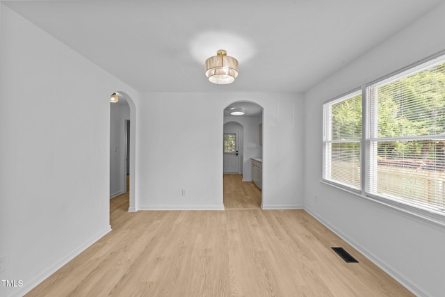 413 Top Greene Ln, Raleigh, NC 27601 - unfurnished room featuring arched walkways, light wood-style floors, healthy amount of natural light, and baseboards
