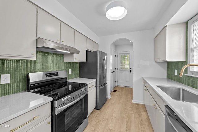 413 Top Greene Ln, Raleigh, NC 27601 - kitchen featuring stainless steel appliances, under cabinet range hood, arched walkways, light wood-type flooring, and a sink