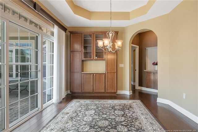 239 Nandina Ct Unit 21A, Fayetteville, NC 28311 - unfurnished dining area featuring a chandelier, dark wood finished floors, arched walkways, and baseboards