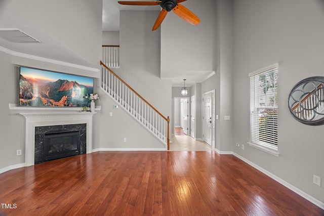 7873 Cape Charles Dr, Raleigh, NC 27617 - unfurnished living room with ceiling fan, a high ceiling, hardwood / wood-style floors, stairway, and a high end fireplace