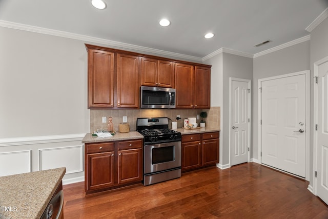 7873 Cape Charles Dr, Raleigh, NC 27617 - kitchen featuring appliances with stainless steel finishes, ornamental molding, decorative backsplash, dark wood-type flooring, and light stone countertops