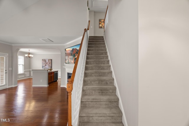 7873 Cape Charles Dr, Raleigh, NC 27617 - stairs featuring wood-type flooring, a chandelier, arched walkways, ornamental molding, and a fireplace