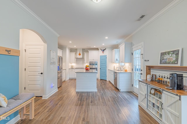 470 E Wellesley Dr, Clayton, NC 27520 - kitchen featuring stainless steel appliances, ornamental molding, wall chimney range hood, tasteful backsplash, and white cabinets