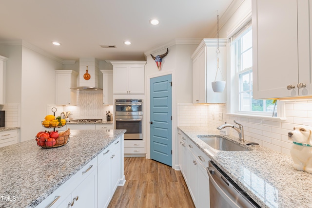 470 E Wellesley Dr, Clayton, NC 27520 - kitchen featuring wall chimney range hood, appliances with stainless steel finishes, white cabinets, ornamental molding, and backsplash