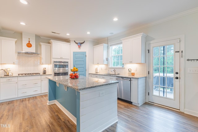 470 E Wellesley Dr, Clayton, NC 27520 - kitchen with appliances with stainless steel finishes, wall chimney range hood, ornamental molding, white cabinetry, and a kitchen island