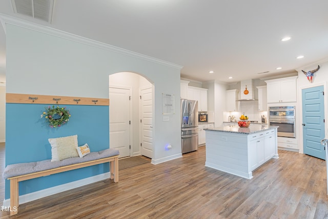 470 E Wellesley Dr, Clayton, NC 27520 - kitchen featuring appliances with stainless steel finishes, arched walkways, ornamental molding, wall chimney range hood, and tasteful backsplash