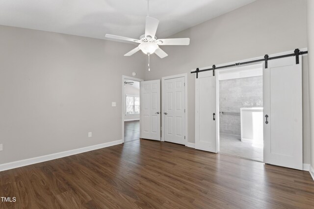 115 Heatherwood Dr, Apex, NC 27502 - unfurnished bedroom with a barn door, a high ceiling, dark wood-style flooring, and baseboards