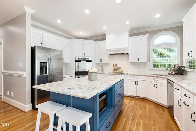 206 W Stoneybrook Ct, Benson, NC 27504 - kitchen featuring appliances with stainless steel finishes, blue cabinets, white cabinetry, a sink, and ornamental molding