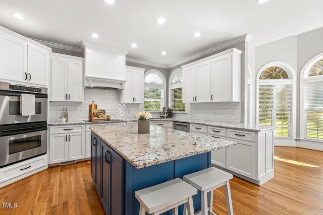 206 W Stoneybrook Ct, Benson, NC 27504 - kitchen with stainless steel appliances, light wood-style flooring, a kitchen bar, white cabinets, and recessed lighting