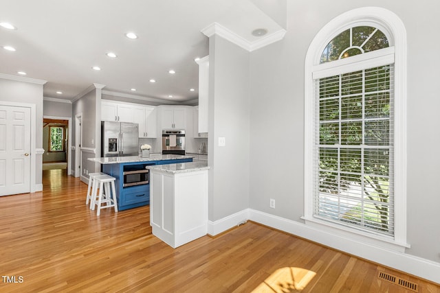 206 W Stoneybrook Ct, Benson, NC 27504 - kitchen featuring stainless steel appliances, ornamental molding, baseboards, white cabinetry, and a kitchen bar