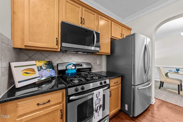 5545 Moneta Ln, Apex, NC 27539 - kitchen with appliances with stainless steel finishes, crown molding, arched walkways, dark wood-type flooring, and backsplash