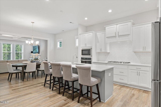 857 Whistable Ave, Wake Forest, NC 27587 - kitchen featuring stainless steel appliances, light countertops, a kitchen island with sink, decorative backsplash, and white cabinets