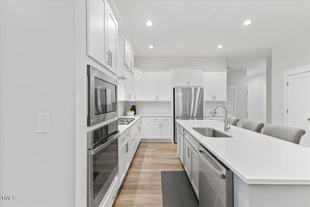 857 Whistable Ave, Wake Forest, NC 27587 - kitchen with appliances with stainless steel finishes, a sink, light countertops, a center island with sink, and backsplash