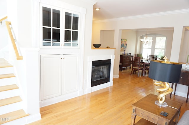 4810 Glenmist Ct, Raleigh, NC 27612 - living room featuring stairs, a chandelier, ornamental molding, light wood-style floors, and a fireplace