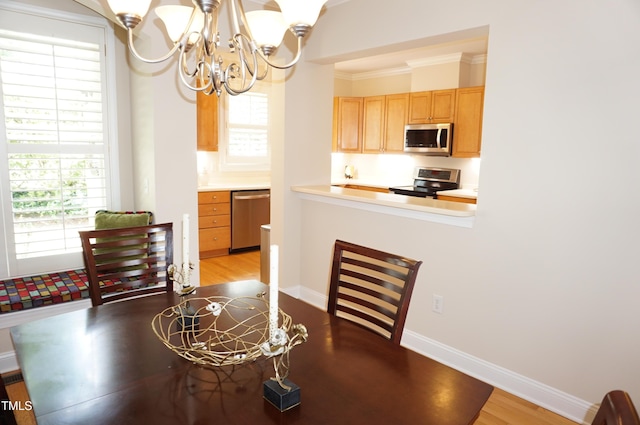 4810 Glenmist Ct, Raleigh, NC 27612 - dining area with a chandelier, light wood-type flooring, baseboards, and crown molding