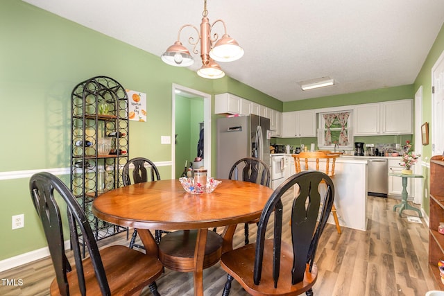 713 Saint Catherines Dr, Wake Forest, NC 27587 - dining room featuring light wood finished floors, a chandelier, and a textured ceiling