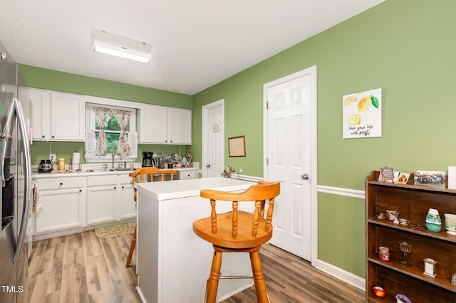 713 Saint Catherines Dr, Wake Forest, NC 27587 - kitchen with light wood finished floors, a kitchen breakfast bar, white cabinetry, stainless steel fridge with ice dispenser, and light countertops