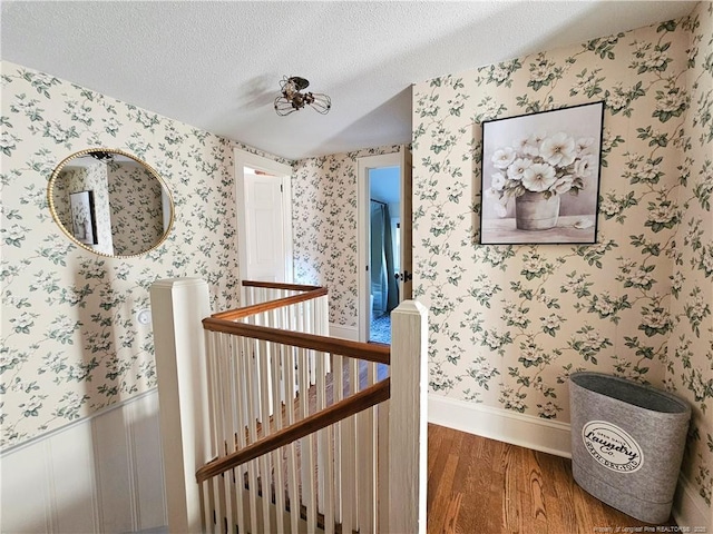 3647 Olivia Rd, Sanford, NC 27332 - hall with an upstairs landing, wood finished floors, wallpapered walls, a textured ceiling, and baseboards