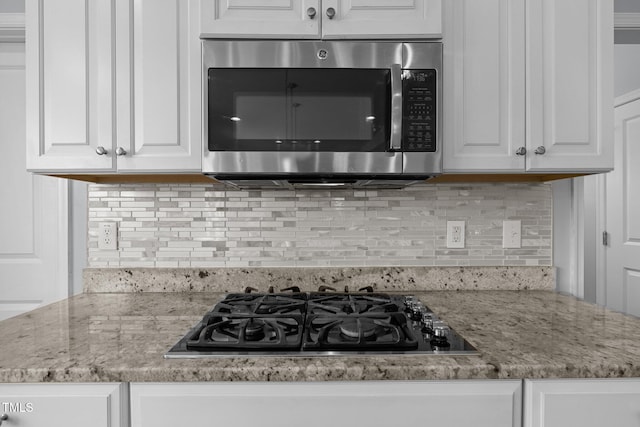 204 Ashland Hill Dr, Holly Springs, NC 27540 - kitchen with stainless steel microwave, black gas cooktop, white cabinets, and tasteful backsplash