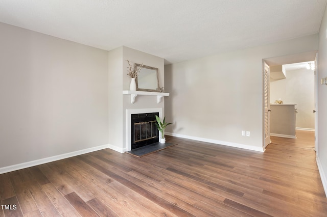 118 Rhum Pl, Garner, NC 27529 - unfurnished living room featuring a glass covered fireplace, wood finished floors, and baseboards