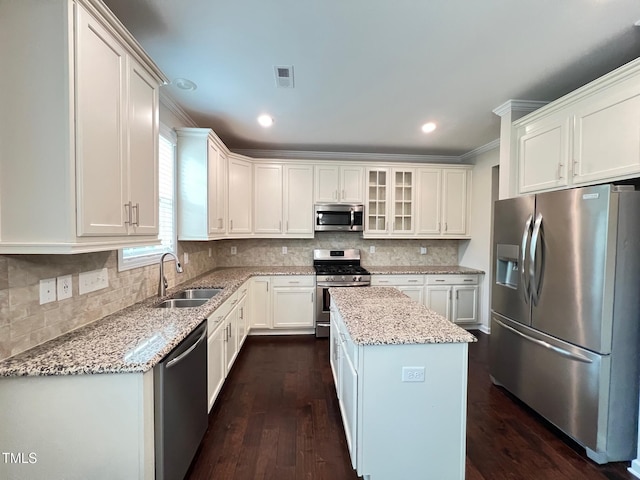 1746 Hammocks Beach Trl, Apex, NC 27502 - kitchen with stainless steel appliances, a sink, a kitchen island, light stone counters, and crown molding