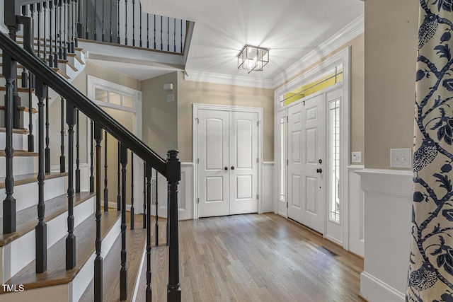 3124 Briar Stream Run, Raleigh, NC 27612 - foyer entrance with a chandelier, wood finished floors, stairs, crown molding, and a wainscoted wall
