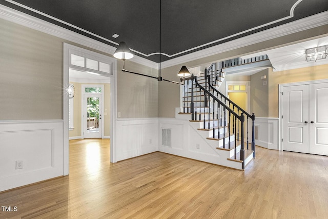 3124 Briar Stream Run, Raleigh, NC 27612 - entrance foyer featuring wood finished floors, a wainscoted wall, a decorative wall, stairway, and crown molding