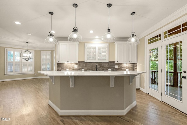 3124 Briar Stream Run, Raleigh, NC 27612 - kitchen featuring ornamental molding, light countertops, white cabinets, tasteful backsplash, and a kitchen island