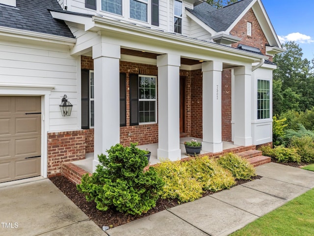 7502 Latteri Ct, Raleigh, NC 27613 - property entrance featuring covered porch, brick siding, roof with shingles, and a garage