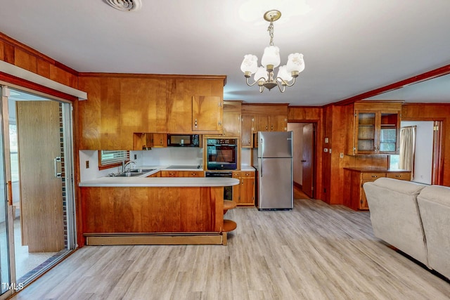 9455 Boston Rd, Roxboro, NC 27574 - kitchen featuring black appliances, brown cabinets, a chandelier, light wood finished floors, and wooden walls