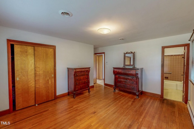 9455 Boston Rd, Roxboro, NC 27574 - bedroom with light wood-style floors, a baseboard heating unit, a closet, baseboards, and ensuite bath
