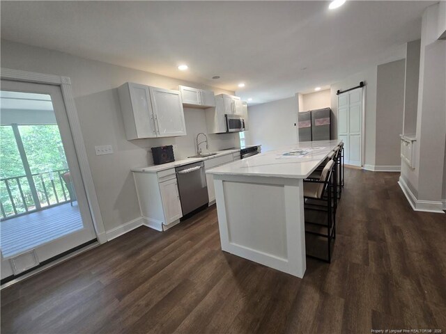 409 Thimbleberry Dr, Vass, NC 28394 - kitchen featuring stainless steel appliances, a sink, a barn door, light countertops, and dark wood-style floors