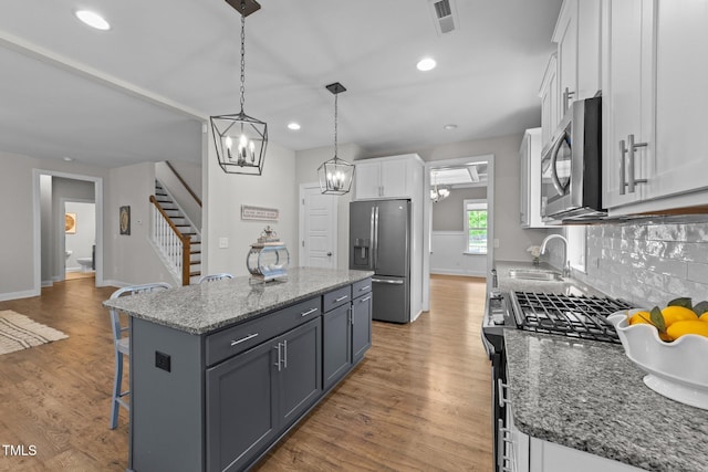 516 Culmore Dr, Fuquay Varina, NC 27526 - kitchen featuring appliances with stainless steel finishes, a sink, a kitchen breakfast bar, white cabinets, and a chandelier