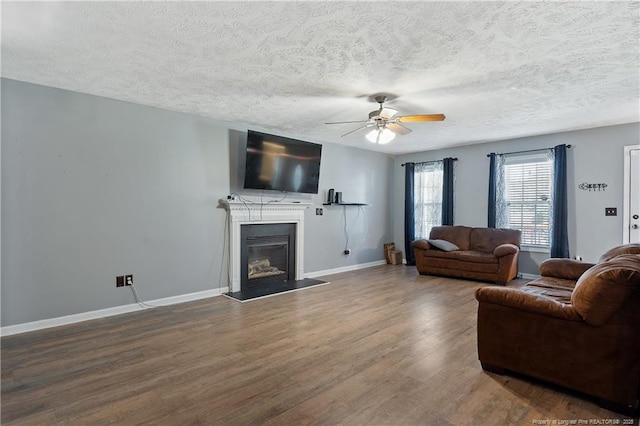 717 Lenoir Dr, Spring Lake, NC 28390 - living room featuring ceiling fan, wood finished floors, a glass covered fireplace, baseboards, and a textured ceiling