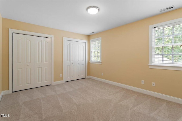 1211 E Pointe Dr, Durham, NC 27712 - unfurnished bedroom with two closets, baseboards, and carpet