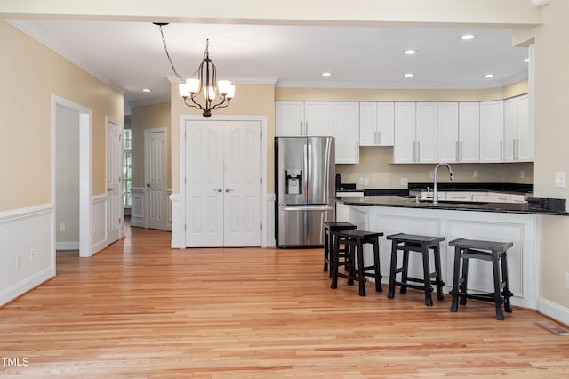 1211 E Pointe Dr, Durham, NC 27712 - kitchen featuring stainless steel fridge, dark countertops, light wood finished floors, a kitchen breakfast bar, and crown molding