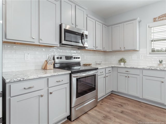 298 Turkey Trot Ln, Raeford, NC 28376 - kitchen with appliances with stainless steel finishes, decorative backsplash, light wood finished floors, and light stone counters