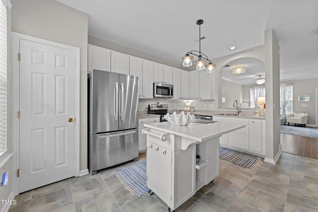 5717 Corbon Crest Ln, Raleigh, NC 27612 - kitchen featuring appliances with stainless steel finishes, light countertops, white cabinets, arched walkways, and a center island