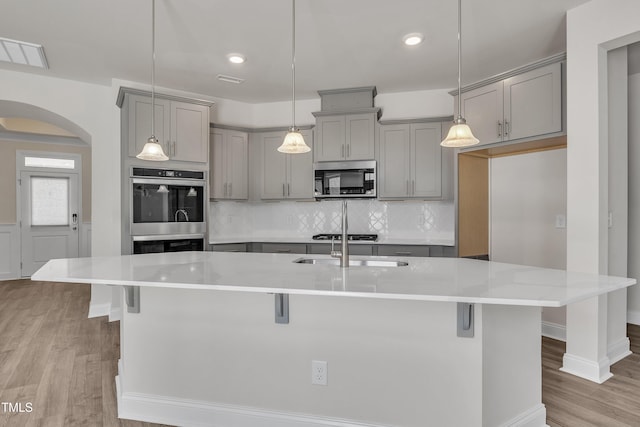 1217 Linkwood Way, Fuquay Varina, NC 27526 - kitchen with gray cabinets, stainless steel appliances, arched walkways, light wood finished floors, and recessed lighting