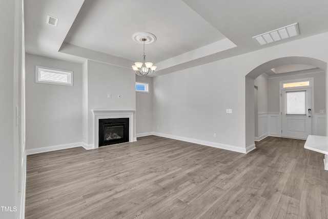 1217 Linkwood Way, Fuquay Varina, NC 27526 - unfurnished living room with a raised ceiling, arched walkways, wood finished floors, and plenty of natural light