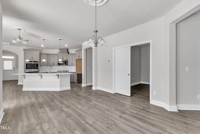 1217 Linkwood Way, Fuquay Varina, NC 27526 - unfurnished living room with a chandelier, a sink, light wood-type flooring, arched walkways, and recessed lighting